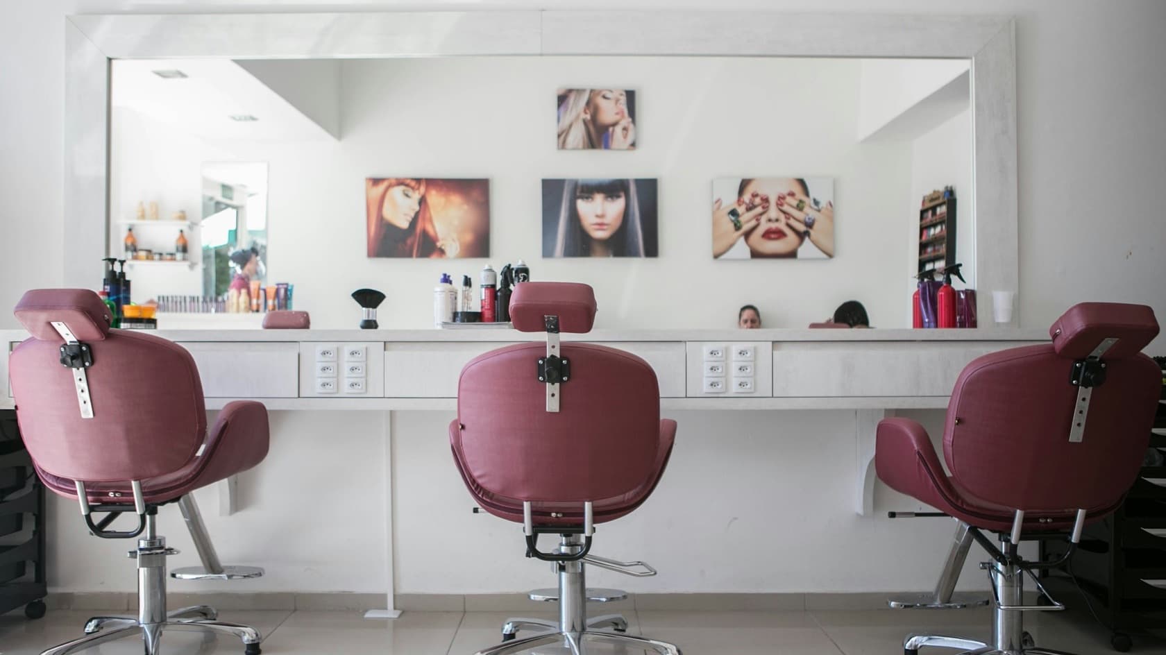 Světlý kadeřnický salon se třemi křesly a velkým zrcadlem